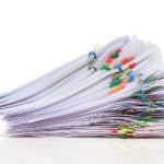 stack of paperwork with colorful paperclips
