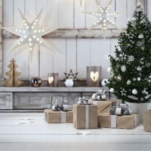 farmhouse style Christmas tree with gifts wrapped in brown paper. simple lighted stars hanging from ceiling.