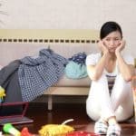 distraught woman sitting on a floor surrounded by clutter. How to help a hoarder.